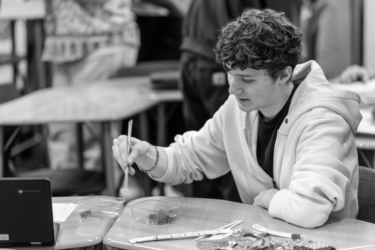 Senior Milo Tobin picks up gummy bears with chopsticks during an AP Stat activity.